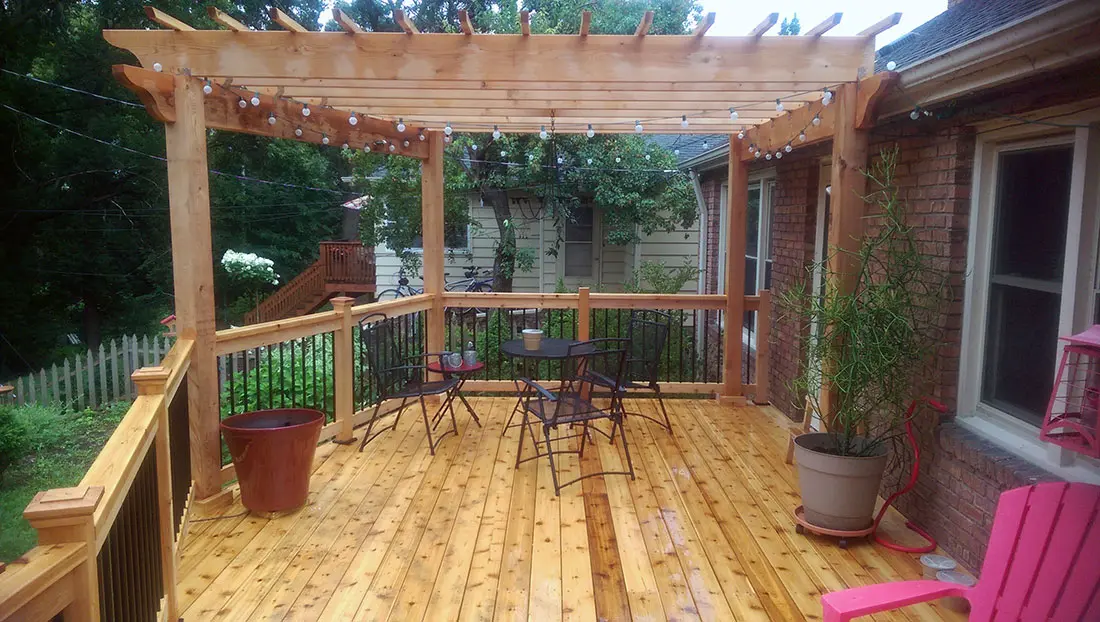 Open pergola over a deck in a leafy yard